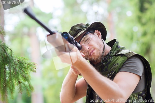 Image of young soldier or hunter with gun in forest