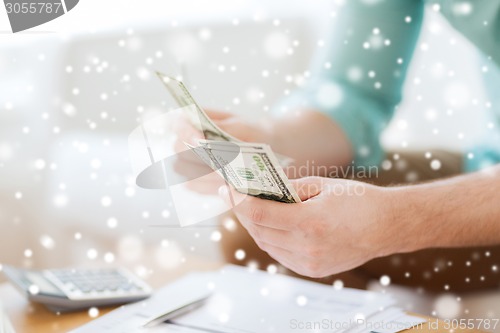 Image of close up of man counting money and making notes