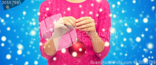 Image of close up of woman in sweater with christmas ball