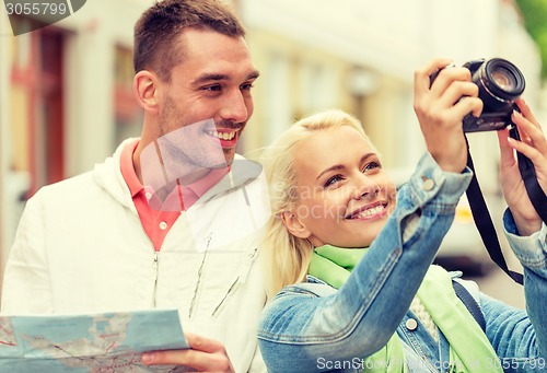 Image of smiling couple with map and photocamera in city