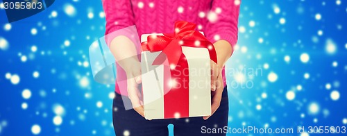 Image of close up of woman in pink sweater holding gift box