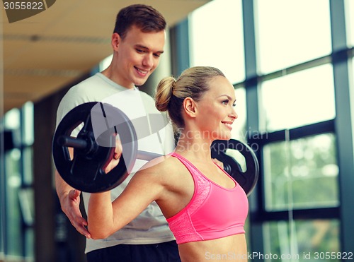 Image of smiling man and woman with barbell in gym