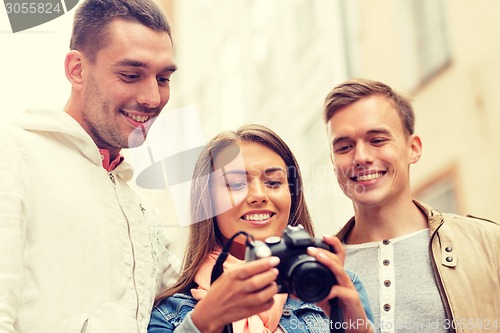 Image of group of smiling friends with digital photocamera