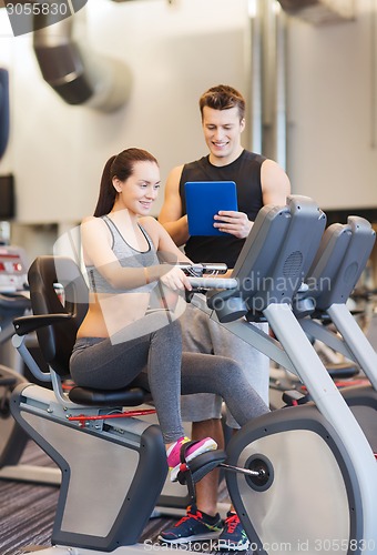 Image of happy woman with trainer on exercise bike in gym