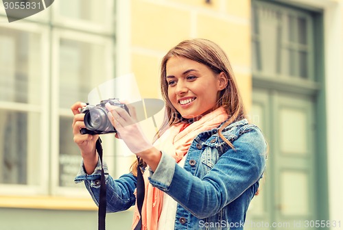 Image of smiling girl with digiral photocamera in the city