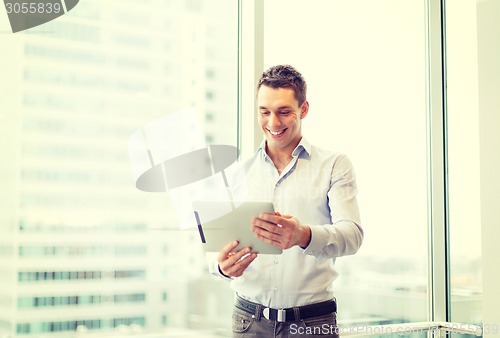 Image of smiling businessman with tablet pc in office