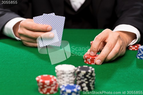 Image of poker player with cards and chips at casino