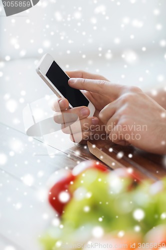 Image of close up of man showing smartphone in kitchen