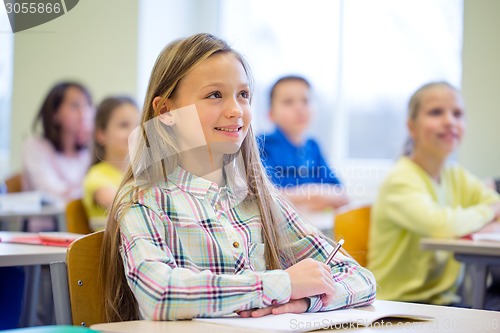 Image of group of school kids with notebooks in classroom