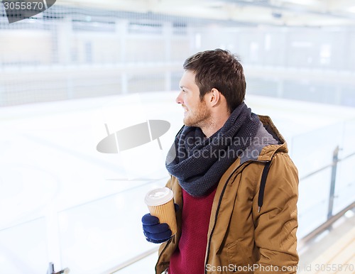Image of happy young man with coffee cup on skating rink