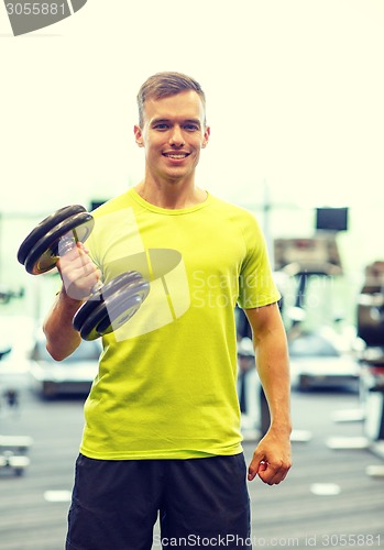 Image of smiling man with dumbbell in gym