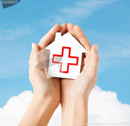 Image of hands holding paper house with red cross