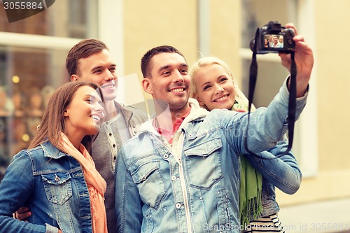 Image of group of smiling friends making selfie outdoors