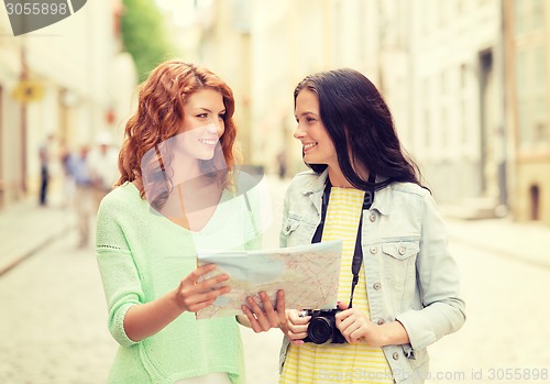 Image of smiling teenage girls with map and camera