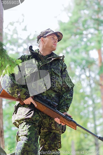 Image of young soldier or hunter with gun in forest