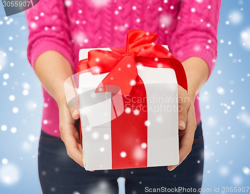 Image of close up of woman in pink sweater holding gift box