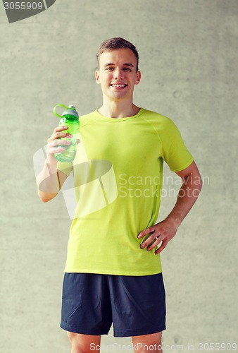 Image of smiling man with bottle of water in gym