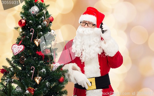 Image of santa claus with smartphone and christmas tree