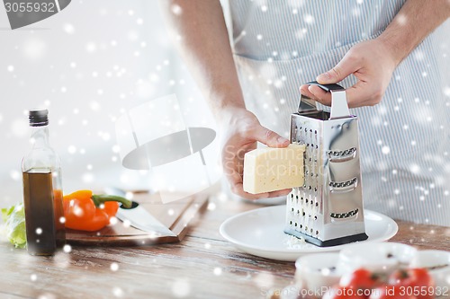 Image of close up of male hands with grater grating cheese