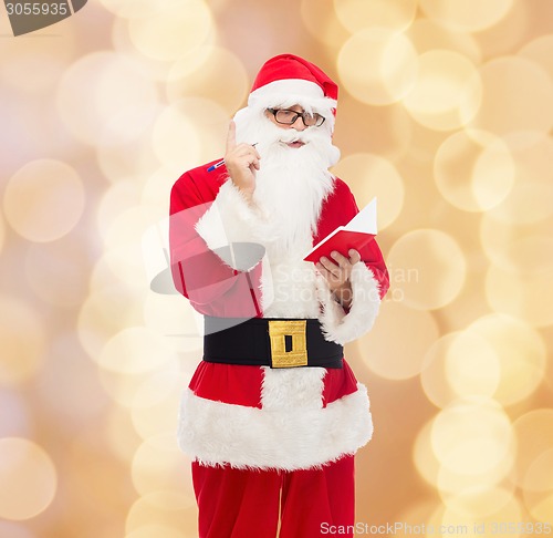 Image of man in costume of santa claus with notepad