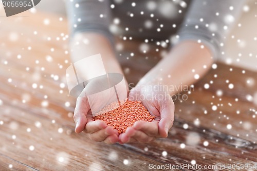 Image of close up of woman emptying jar with red lentils