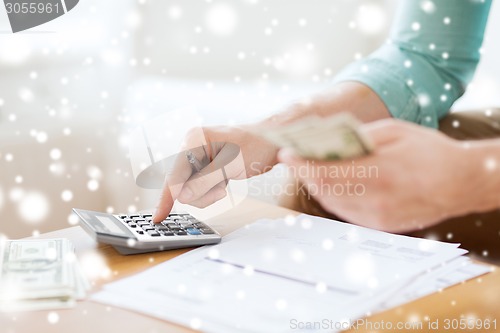 Image of close up of man counting money and making notes