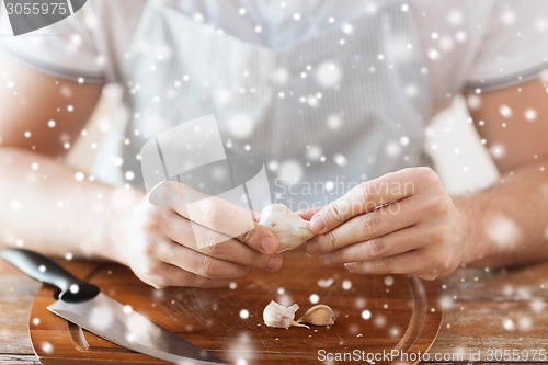 Image of close up of male hands taking off garlic peel