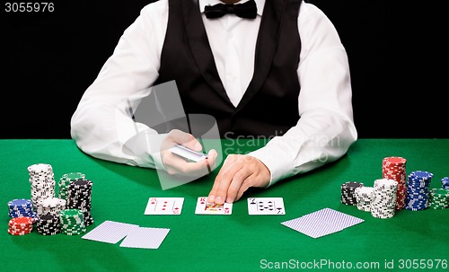 Image of holdem dealer with playing cards and casino chips