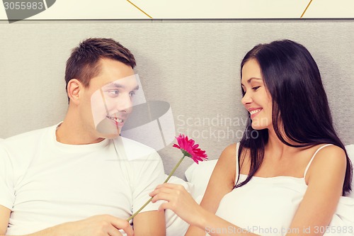 Image of smiling couple in bed with flower