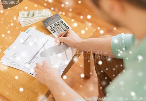 Image of close up of man counting money and making notes