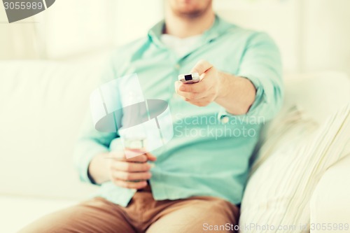 Image of man with beer and remote control at home