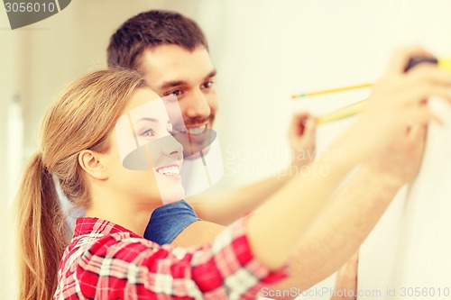 Image of smiling couple measuring wall