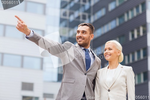 Image of smiling businessmen standing over office building