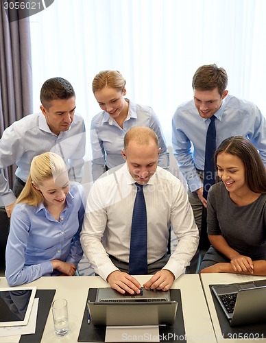 Image of smiling business people with laptop in office