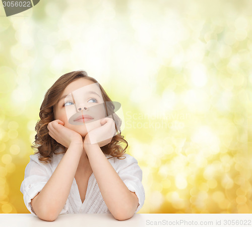 Image of beautiful girl sitting at table and looking up