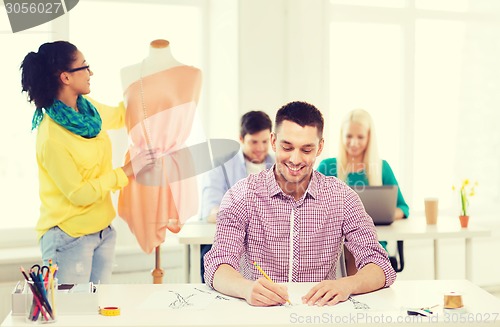 Image of smiling fashion designers working in office