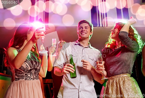 Image of smiling friends with wine glasses and beer in club