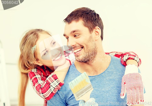 Image of smiling couple covered with paint with paint brush