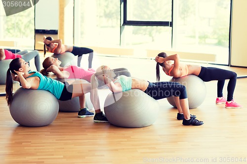 Image of group of smiling women with exercise balls in gym