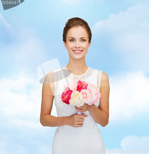 Image of smiling woman in white dress with bouquet of roses