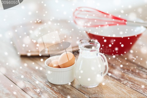 Image of close up of milk jug, eggs, whisk and flour