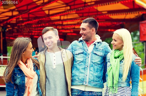 Image of group of smiling friends in amusement park