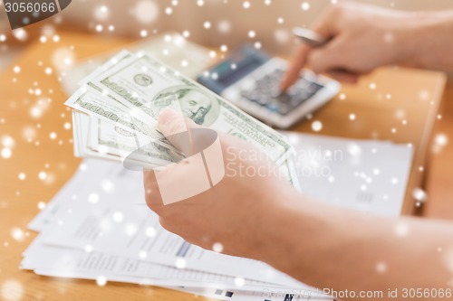 Image of close up of man counting money and making notes