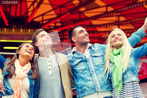 Image of group of smiling friends in amusement park