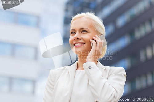 Image of smiling businesswoman with smartphone outdoors