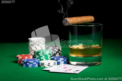 Image of close up of chips, cards whisky and cigar on table