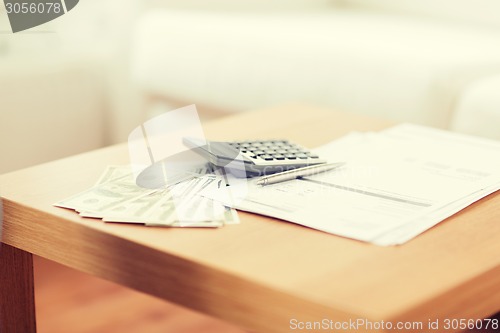 Image of close up of money and calculator on table at home