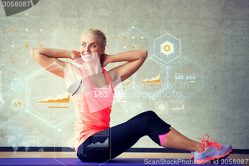 Image of smiling woman doing exercises on mat in gym