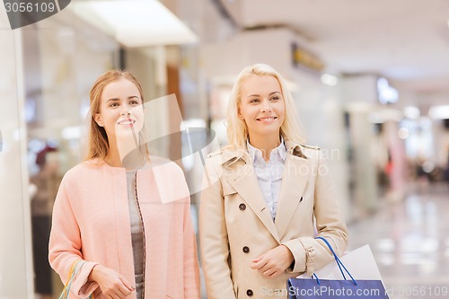 Image of happy young women with shopping bags in mall