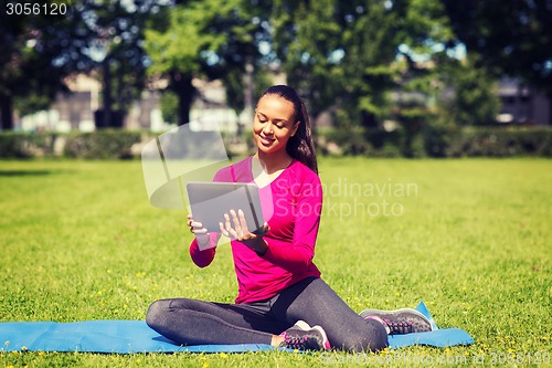 Image of smiling woman with tablet pc outdoors